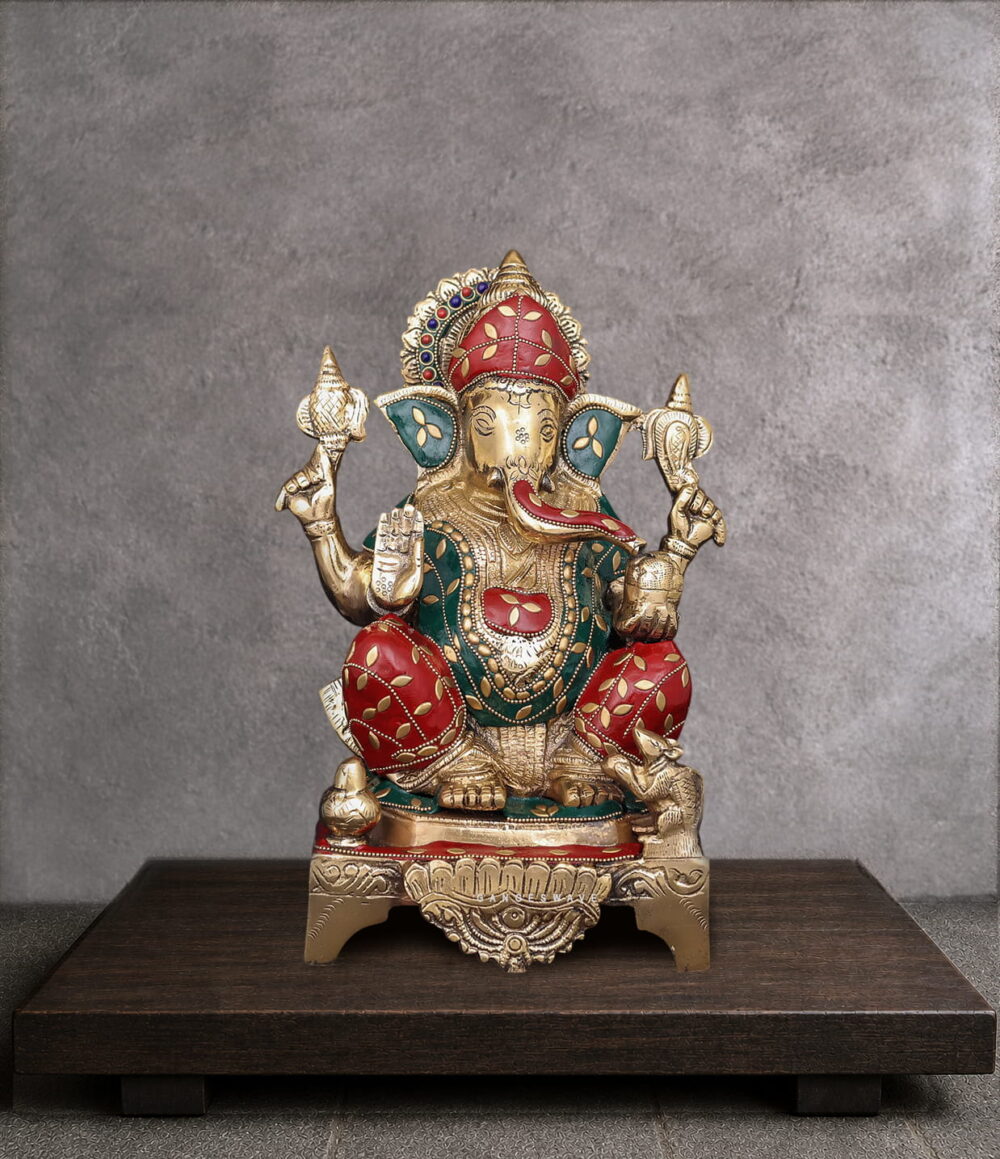 Handcrafted brass Lord Ganesha idol with traditional red and green Meenakari artwork, seated on an ornate pedestal for home temple and luxury interior décor.