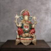 Handcrafted brass Lord Ganesha idol with traditional red and green Meenakari artwork, seated on an ornate pedestal for home temple and luxury interior décor.