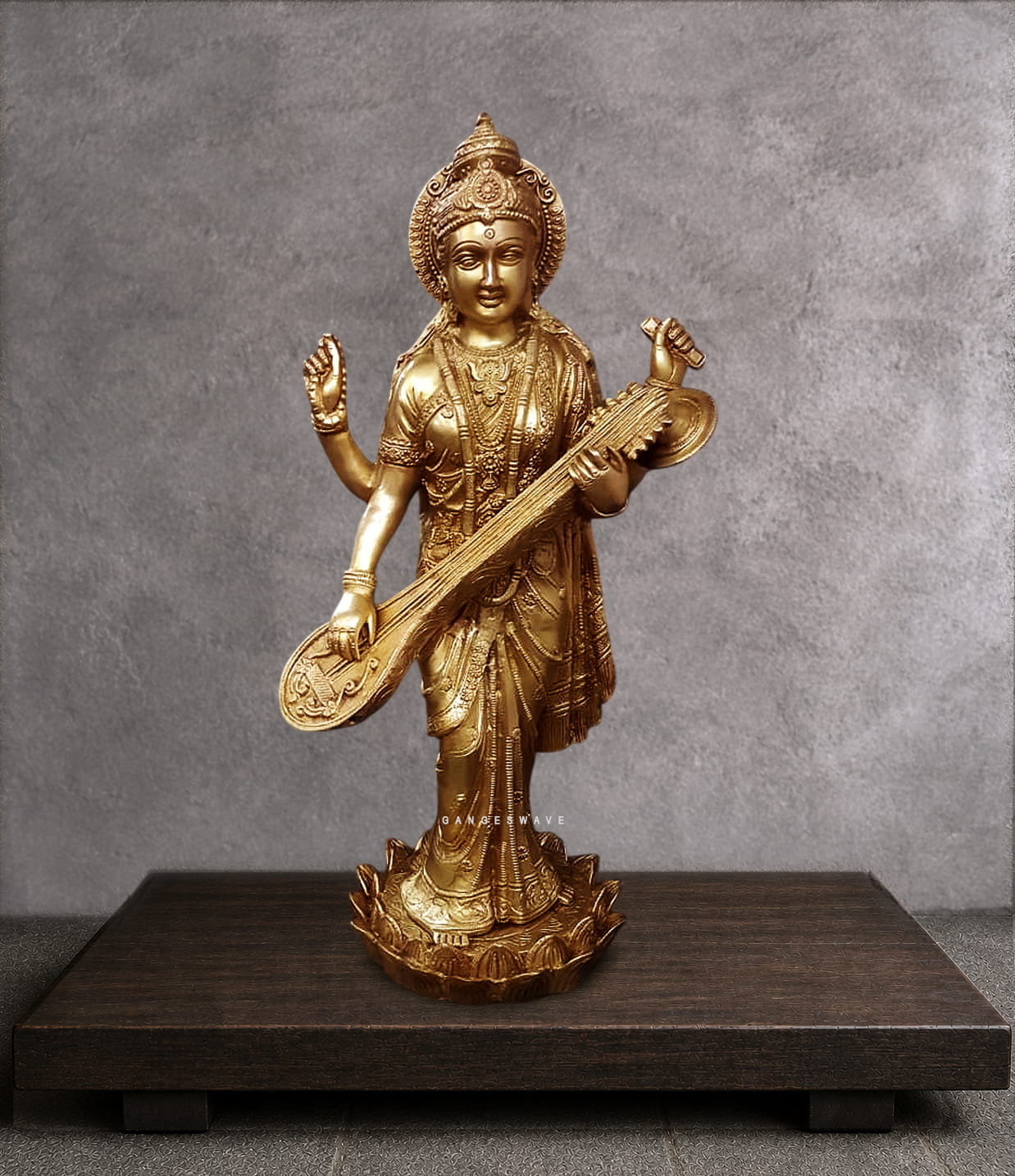 Close-up detail of brass Saraswati idol face showing serene meditative expression, ornate jeweled crown with floral motifs, third eye, and traditional Indian goddess ornamentation. Handcrafted brass deity facial detail.