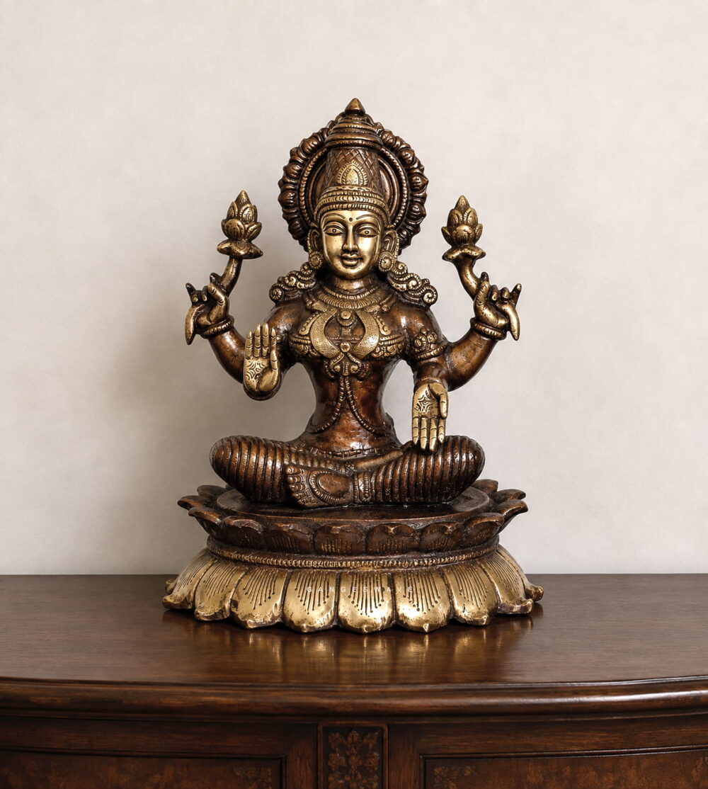 Premium handcrafted Brass Goddess Lakshmi Idol seated on a lotus pedestal with intricate temple-style carvings, antique dual-tone finish, and lotus flowers for home temple, Diwali Puja, Vaastu, and luxury spiritual décor.