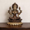Premium handcrafted Brass Goddess Lakshmi Idol seated on a lotus pedestal with intricate temple-style carvings, antique dual-tone finish, and lotus flowers for home temple, Diwali Puja, Vaastu, and luxury spiritual décor.