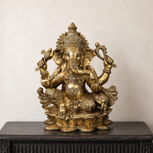 Brass Ganesha idol sitting on a lotus pedestal with intricate traditional detailing
