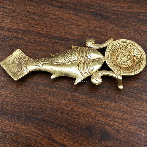 Handcrafted brass puja spoon featuring an ornate fish-inspired form and engraved lotus motif.