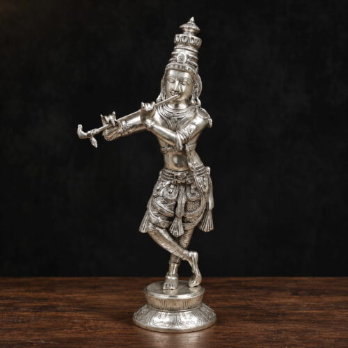 Silver-plated brass Krishna statue playing the flute with an ornate crown and decorative pedestal
